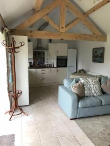 a living room with a blue couch and a kitchen at Pretty Garden Cottage in Tollerton +6 photos