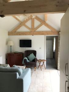 a living room with a couch and a tv at Pretty Garden Cottage in Tollerton