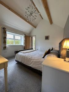 a bedroom with a bed and a table and a lamp at Pretty Garden Cottage in Tollerton