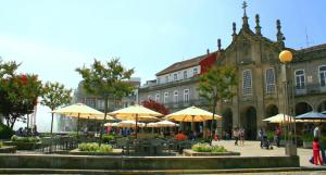 Flat Accommodation in Braga في براغا: ساحة فيها طاولات ومظلات امام المبنى