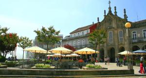 einen Innenhof mit Tischen und Sonnenschirmen vor einem Gebäude in der Unterkunft Flat Accommodation in Braga in Braga