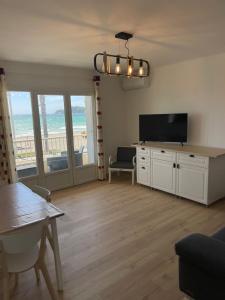 een woonkamer met een flatscreen-tv en een tafel bij la plage in Six-Fours-les-Plages