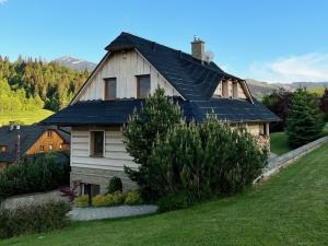 a house with a black roof on a green field at Drevenica Nela - Chalet in Tatras in Zuberec