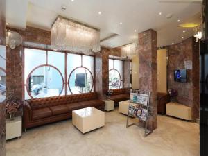 a living room with a brown leather couch and windows at Hotel ACME in Kolkata