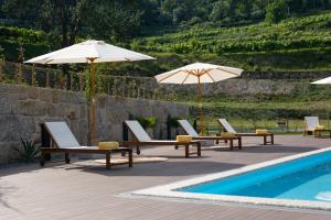 a group of chairs and umbrellas next to a pool at Quinta de Reis in Ponte da Barca