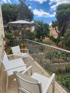 balkon z białymi krzesłami i parasolem w obiekcie Dimora Liberty w mieście Lecce