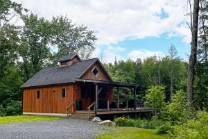 a large wooden cabin in the woods with a porch at Newly Built Cabin with Hot Tub - 16 Mi to Stowe Mtn! in Morristown