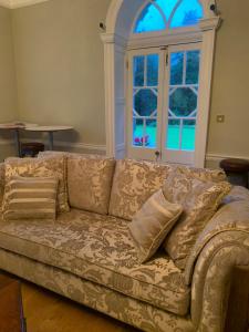 a couch with pillows in a living room with a window at Lisglassock House in Longford
