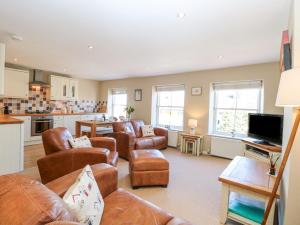 a living room with leather furniture and a kitchen at Crab Corner in Wells next the Sea