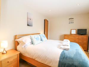a bedroom with a bed and a dresser and a television at Crab Corner in Wells next the Sea