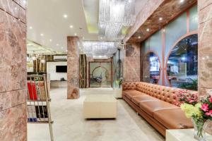 a lobby with a brown leather couch and flowers at Hotel ACME in Kolkata