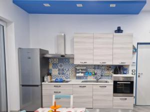 a kitchen with white cabinets and a blue ceiling at Casetta 28 passi dal mare in Acquappesa