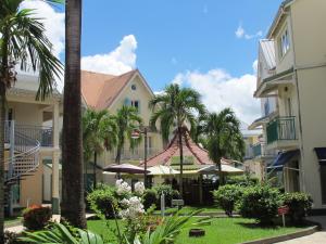 a building with palm trees and a gazebo at Village Creole in Les Trois-Îlets