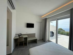 a bedroom with a bed and a desk and a balcony at Villa Mimosa Florital - Free Private Parking On site & in Tropea in Santa Domenica