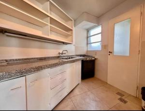 eine Küche mit weißen Schränken und einer Spüle und einem Fenster in der Unterkunft Departamento centro Mendoza a Pasos de la terminal in Barraquero