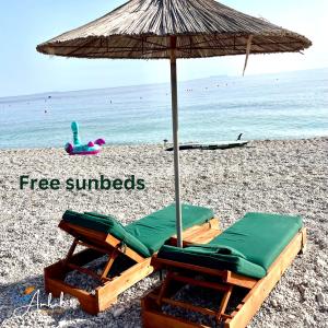 two lounge chairs and an umbrella on a beach at Chalet Ambel in Dhërmi