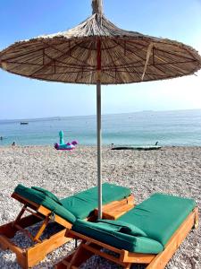 a beach chair with an umbrella on a beach at Chalet Ambel in Dhërmi