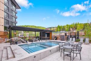 a patio with a pool and tables and chairs at Electric Pass Lodge by Snowmass Vacations in Snowmass Village