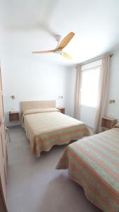 sypialnia z 2 łóżkami i wentylatorem sufitowym w obiekcie Casa Cuartel El Delfín w Maladze