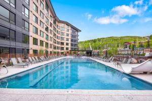a swimming pool in a hotel with chairs and a building at Electric Pass Lodge by Snowmass Vacations in Snowmass Village