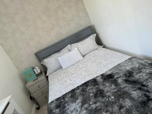 1 dormitorio con 1 cama con edredón gris y blanco en Home away home, en Great Barr