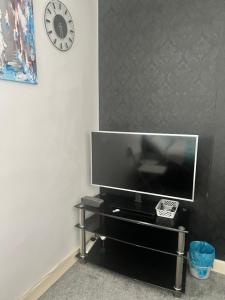 a flat screen tv on a black entertainment center with a clock at Tilbury Home For short letting in Tilbury