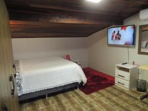 a bedroom with a bed and a flat screen tv at Pousada Cusco - Centro de Jaraguá do Sul in Jaraguá do Sul