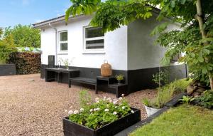 アリンエにあるCozy Home In Allinge With Wifiの庭の花とベンチ付きの家 +16枚の写真