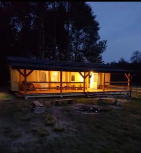 a house with lights on in a field at night at Uroczy domek letniskowy w otoczeniu przyrody in Błonie