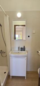 a white bathroom with a sink and a mirror at APARTMANI SANDRA PRPIĆ in Rab