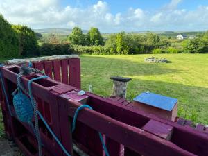 a red wooden fence with a field in the background at Puffin rooms in Lisdoonvarna