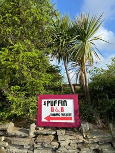 a sign for a hotel with a palm tree in the background at Puffin rooms in Lisdoonvarna