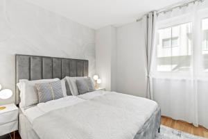 une chambre blanche avec un grand lit et une fenêtre dans l'établissement Modern Apartment I Parking I Vienna, à Vienne