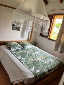 a bed with a green and white comforter and a window at Mango Sea -Villa "Maracudja" et appartement "Jojoba" avec piscine & vue sur les îles in Saint-François +32 photos