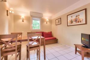 a living room with a red couch and a table at Résidence Les Grands Pins - maeva Home - Appartement 2 pièces 4 personnes - Sélection MAE-3004 in Maubuisson