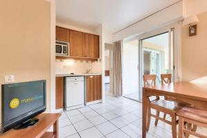 a kitchen and dining room with a table and a television at Résidence Les Grands Pins - maeva Home - Appartement 2 pièces 4 personnes - Sélection MAE-3004 in Maubuisson