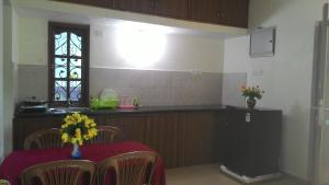 a kitchen with a table and a counter with a window at Antonio's Residency Goa in Betalbatim
