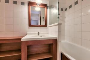 a bathroom with a sink and a mirror and a tub at Résidence Les Grands Pins - maeva Home - Appartement 2 pièces 5 personnes - Confort MAE-0384 in Maubuisson +12 photos