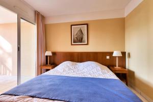 a bedroom with a blue bed with two lamps at Résidence Les Grands Pins - maeva Home - Appartement 2 pièces 5 personnes - Confort MAE-0384 in Maubuisson