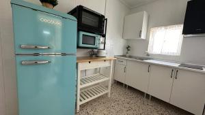 einen blauen Kühlschrank in einer Küche mit Mikrowelle in der Unterkunft Susurros del Mar in Conil de la Frontera