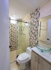 une salle de bain avec toilettes et douche en verre dans l'établissement Tú hogar, tú tranquilidad, à Manizales