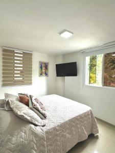une chambre avec un lit et une télévision à écran plat dans l'établissement Tú hogar, tú tranquilidad, à Manizales