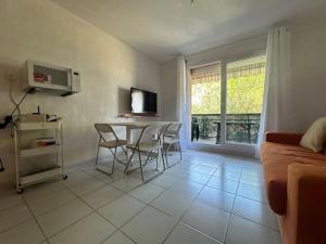 Una sala de estar con un sofá, una mesa y sillas. en Grand studio proche plages, en La Londe-les-Maures