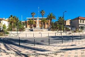 Un patio con palmeras y un edificio. en Grand studio proche plages, en La Londe-les-Maures