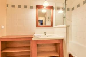 a bathroom with a sink and a mirror and a tub at Résidence Les Grands Pins - maeva Home - Appartement 2 pièces 5 personnes - Sélection MAE-2171 in Maubuisson +13 photos