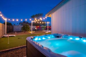 a hot tub in a backyard at night with lights at Mini Golf Fire Pit Pool Game Room in Chandler