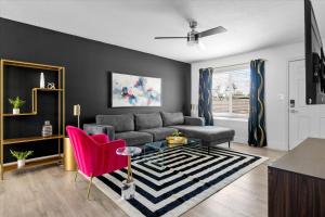a living room with a gray couch and pink chairs at Mini Golf Fire Pit Pool Game Room in Chandler