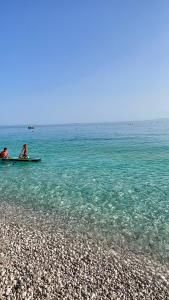 two people are sitting on a boat in the water at Chalet Ambel in Dhërmi