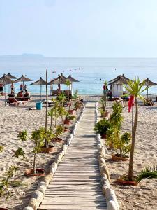 a boardwalk on the beach with palm trees and umbrellas at Chalet Ambel in Dhërmi