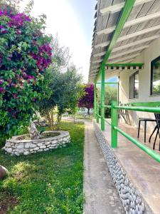 a building with a green railing and a garden with flowers at Chalet Ambel in Dhërmi